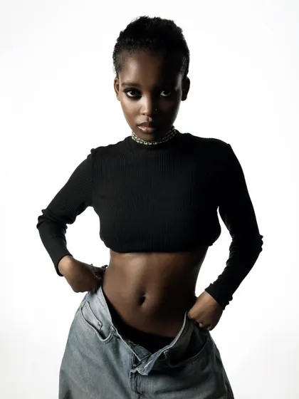 A confident and direct studio portrait. The clean lighting and simple styling ensure the focus is entirely on the model.