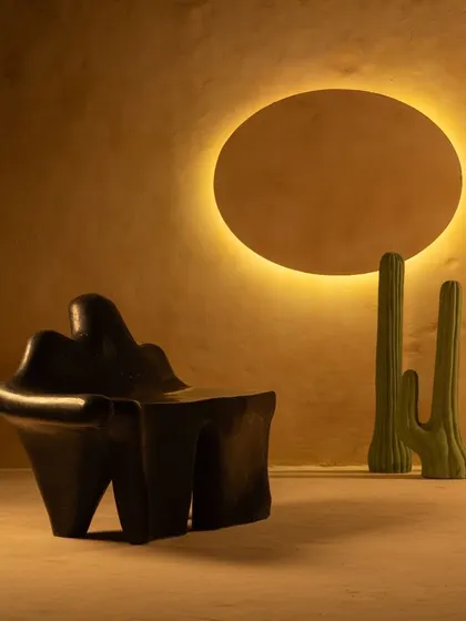 The Coral Seating bench in a dark terrazzo finish, set against a warm, glowing backdrop. Its sculptural form is designed to be an expressive piece for both indoor and outdoor spaces.