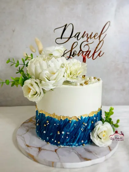 A professional shot of the blue and white floral engagement cake. The marble base and custom topper complete the look.