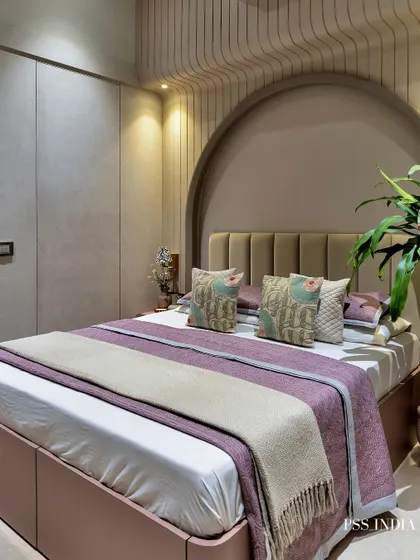 Soft minimalism with a touch of color. This bedroom features a beautiful arched alcove and fluted wall panels, with pops of mauve and dusty pink in the bedding to add warmth and personality to the neutral space.