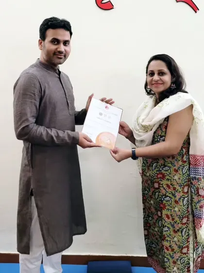 A student receives her 200-hour YTTC certificate. This moment marks the culmination of her hard work and the start of her teaching career.
