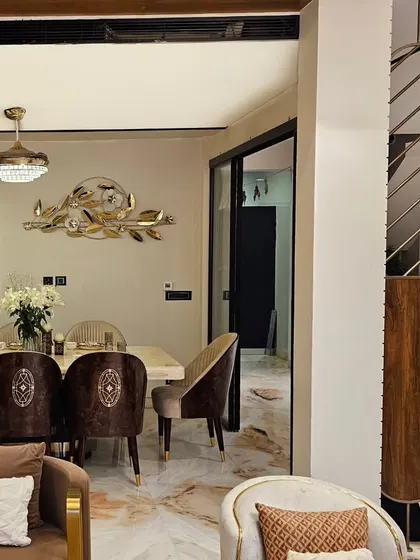 A close-up of the finished dining space, showing the custom chairs with intricate back detailing and the elegant partition that separates the living and dining zones.