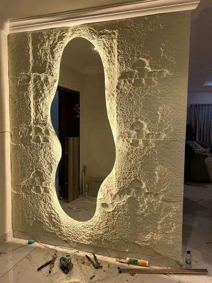 A unique dressing mirror design where the mirror is set into a custom-made, textured stone-like panel with backlighting, creating a very artistic and organic look.