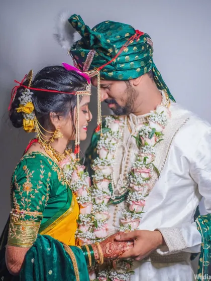 A beautiful portrait of a Maharashtrian couple, capturing the rich colors of the bride's yellow and green saree and the groom's traditional attire.