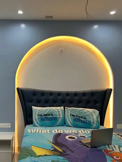 The completed kid's bedroom with the arched backlit headboard, showcasing the final look with bedding and a laptop.
