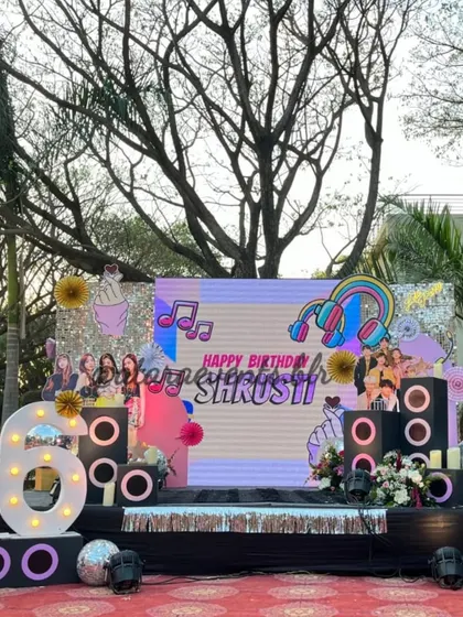 The full stage setup for a K-Pop themed 16th birthday. The large LED screen, speaker props, and marquee lights create an impressive and professional-looking stage for the celebration.