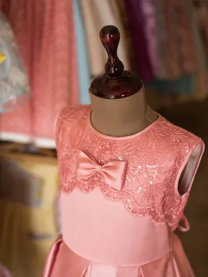 This mannequin shot provides a clear view of the pink lace bodice, showing how it creates a beautiful and sophisticated neckline.