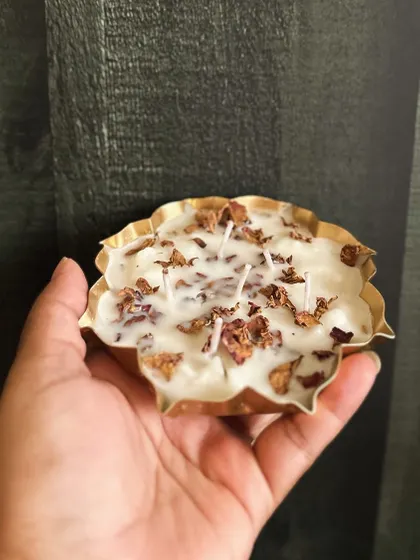 Holding a beautiful copper urli candle filled with soy wax and decorated with dried rose petals.