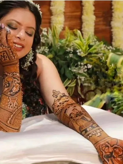 A candid shot of a bride admiring her portrait mehndi, which includes a couple scene and personalized initials on the palm.
