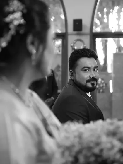 A black and white shot of the groom looking lovingly at his bride during their church ceremony.