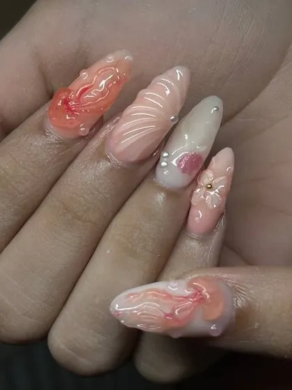Another angle of the beach-inspired nail art, highlighting the different shapes and textures on each nail, from shells to flowers.