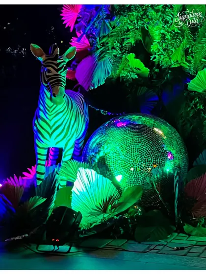 This is the energy I love to create. For this 'Neon Jungle' birthday, I combined lush greenery with vibrant UV lighting, a life-sized zebra prop, and a giant disco ball to craft an immersive, high-energy party atmosphere reminiscent of Studio 54.