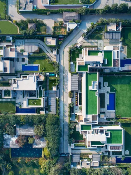 This drone photograph shows a cluster of five sister homes we designed to balance privacy with a connection to nature. Each Vastu-compliant home opens into its own green landscape with pools and rooftop gardens, creating a private oasis within a cohesive micro-community.
