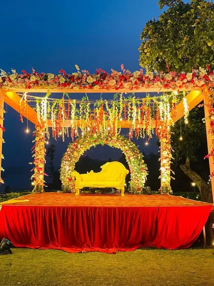 The fully lit outdoor mandap at night, showcasing the beautiful combination of warm lights and colorful floral decorations.