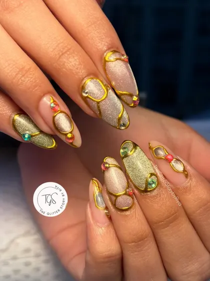 An ornate and luxurious design featuring sculpted gold lines over a shimmery cat-eye base. The look is completed with carefully placed colorful gems for a jewelry-like effect.