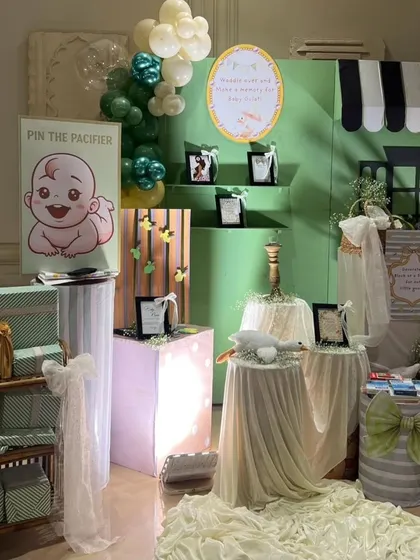 The gift and activity corner for the baby shower, featuring a "Pin the Pacifier" game and beautifully wrapped presents.