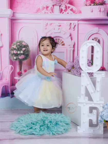 Standing by the light-up "ONE" blocks, this portrait celebrates her big milestone in a dreamy, pastel-colored studio setting.