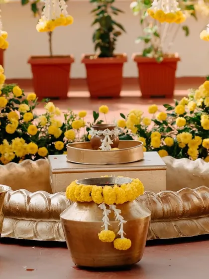 Traditional brass pots and lotus-shaped bowls filled with marigolds, ready for the Haldi ceremony rituals.