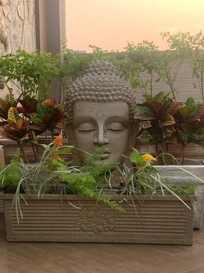 A key element of my styling is creating a sense of peace, often through Zen-inspired decor. This planter, featuring a serene Buddha head surrounded by colorful crotons and other foliage, instantly becomes a tranquil focal point on a terrace.