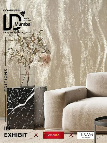 A promotional image for India Design highlighting our partnership with Texam. The wallcovering shown has a beautiful, flowing texture reminiscent of natural stone or plaster, set in a chic, minimalist interior.