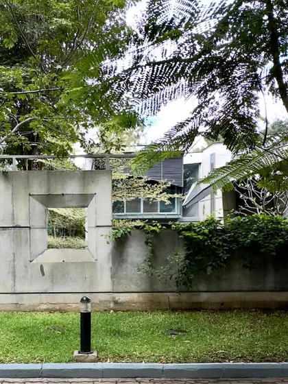 The boundary wall of the 'House of Stories' features carefully placed openings, offering glimpses of the green space within. This approach creates a gentle transition between the public street and the private sanctuary of the home.