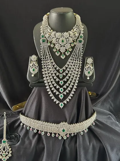 This breathtaking silver-toned bridal set is studded with high-quality white and green stones. The multi-layered necklace and grand choker are designed for a dazzling reception look.