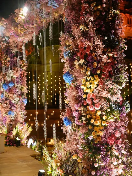The intricate floral work on the mandap pillars, showcasing a vibrant mix of colors and textures that come alive under the evening lights.