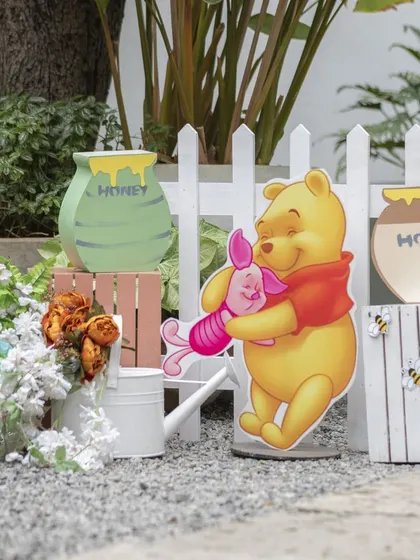 Props from the 'Winnie the Pooh' party, including Pooh and Piglet cutouts and 'hunny' pots. These details help create an immersive experience for the children.