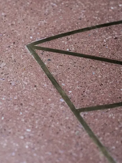 An extreme close-up of the brass inlay, highlighting the clean lines and the texture of the surrounding terrazzo.