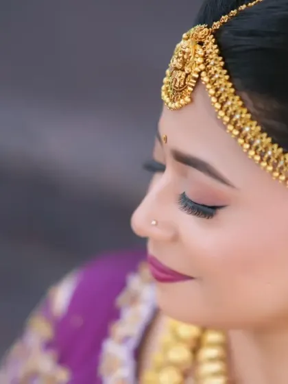 A close-up shot of a bride wearing a traditional gold maang tikka, showing its intricate design.