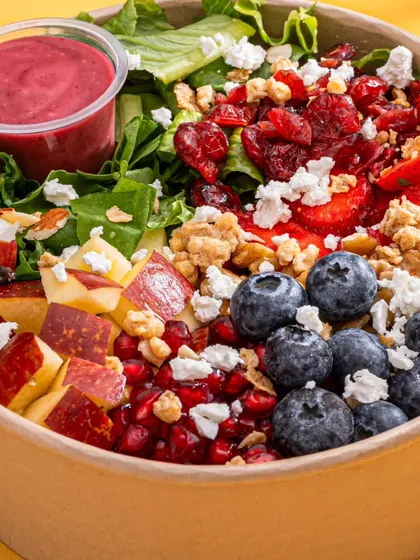 A vibrant and colorful fruit and nut salad from Herbivore Farms. This clean, top-down shot highlights the freshness and variety of the ingredients, perfect for a healthy food brand.