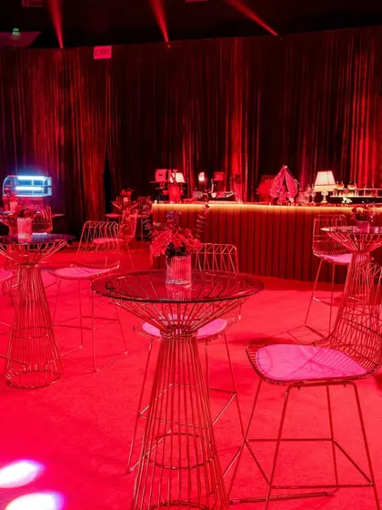 The cocktail lounge area, bathed in a monochromatic red light, creating an intensely moody and immersive atmosphere for guests to mingle.