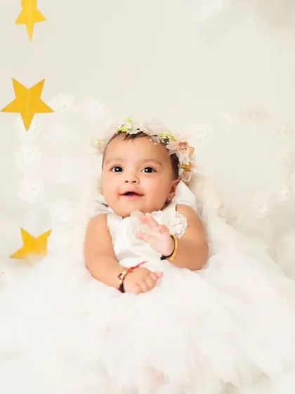 This shot captures a sweet, interactive moment as the baby reaches out. It adds a touch of life and movement to the angelic scene.