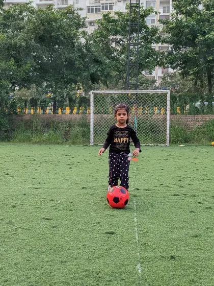 Taking her first steps in football. This young player stands confidently with her ball, ready to learn and play.