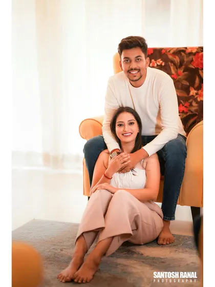 A sweet indoor portrait of a couple sitting together, creating a comfortable and relaxed vibe.