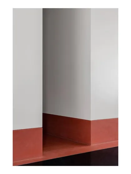 This abstract detail highlights the high skirting made from a terracotta-hued material, which runs along the periphery of the main living areas. It's a continuous line that ties the different spaces together.