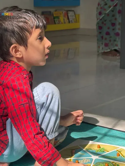 A child is captivated by a puzzle, his focus demonstrating the deep concentration that our learning materials are designed to inspire.