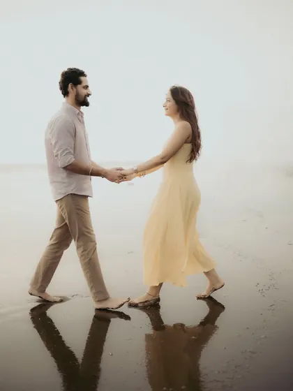 Walking hand-in-hand, reflected in the tide. This shot captures the simple romance of a pre-wedding stroll on the beach.
