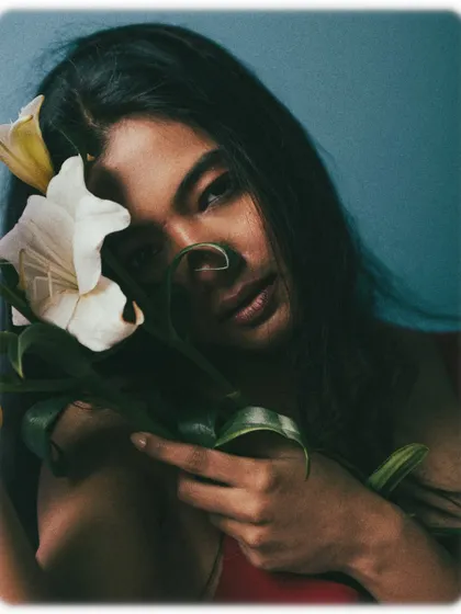 A soft and romantic portrait with the model embracing a white lily. The lighting is gentle and flattering.