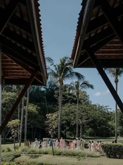 A creative architectural shot framing the distant Baraat procession in Thailand. I use the venue's unique features to create artistic and memorable compositions.