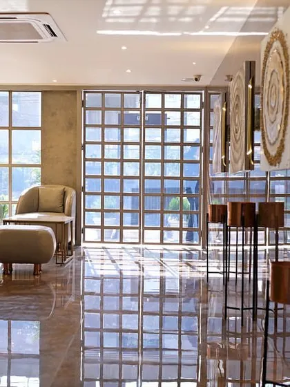 A wider perspective of the hotel lounge, showing the interplay of light and reflection. The custom art pieces and wooden pedestal installations add an artistic, gallery-like feel to the commercial space.
