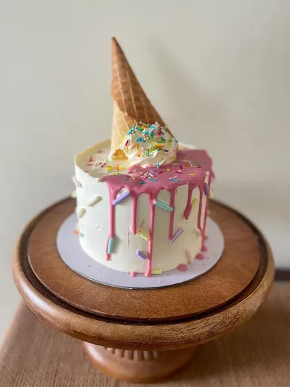 You scream, I scream! An adorable mini cake designed to look like a melting ice cream cone, complete with a pink drip and colorful sprinkles.