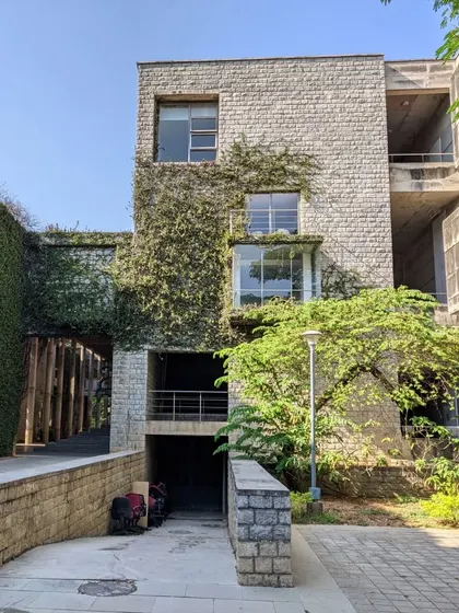 The brutalist stone architecture of IIM Bangalore is softened by climbing ivy and lush greenery, demonstrating how buildings and landscapes can mature together over time.