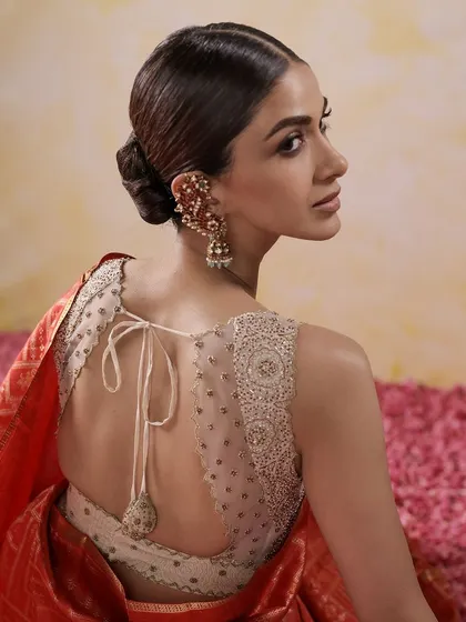 A modern take on the bridal blouse, featuring a sheer back with scattered beadwork and an elegant tie-up tassel. This design offers a contemporary feel while maintaining traditional craftsmanship.