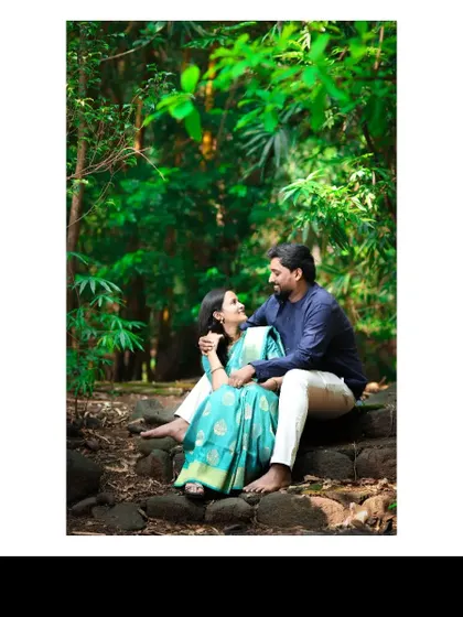 A romantic pre-wedding portrait of a couple sitting closely on stone steps in a forest, sharing an intimate look that speaks volumes about their love.