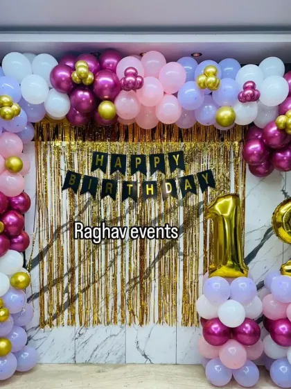 A pretty wall decoration for a 19th birthday. The setup features a balloon arch in shades of pink and purple with gold accents, a gold shimmer curtain, and large number foil balloons.