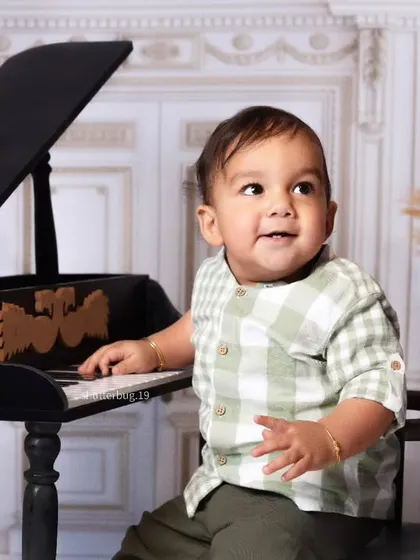 A close-up shot of a baby boy curiously touching the keys of the piano.
