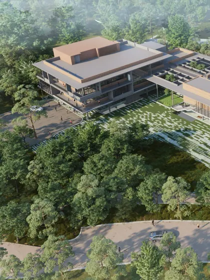 An aerial rendering of the Mahindra University project, showing its integration within a dense green landscape. The design respects the existing topography and uses it to create a multi-level program of activities.