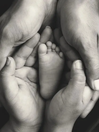 Sometimes, the biggest love is found in the tiniest details. This classic black and white photo focuses on a newborn's perfect little foot held safely in their parents' hands, a timeless symbol of protection, love, and a new beginning.