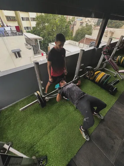 A wide-angle view of a client performing a bench press under my supervision, showcasing the safe and supportive training environment.